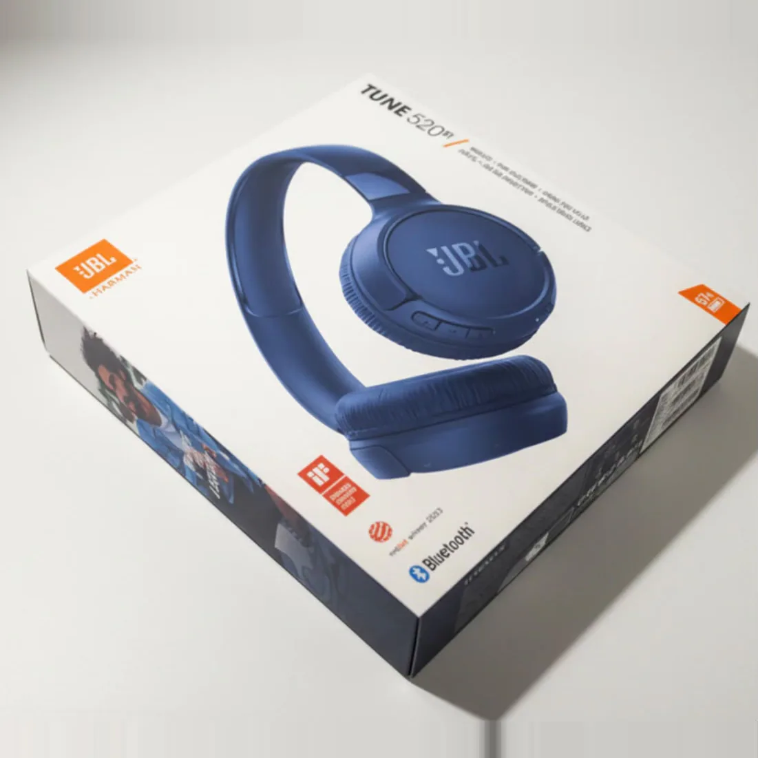 Caixa do fone de ouvido JBL Tune 520BT, com o fone azul estampado, sobre uma superfície clara.